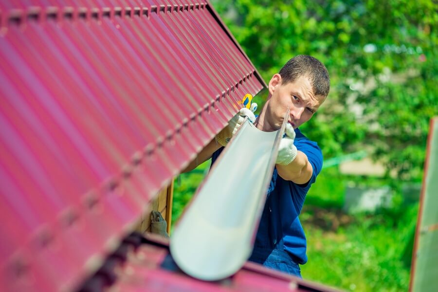 Un homme vérifiant le tuyau pour drainer l'eau de pluie du toit