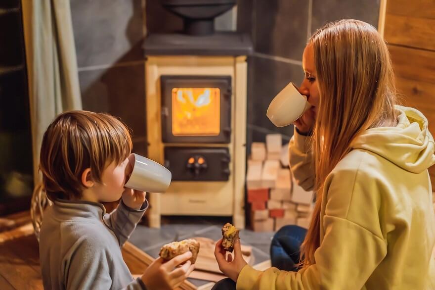 Mère et fils profitant la chaleur de la poêle à bois