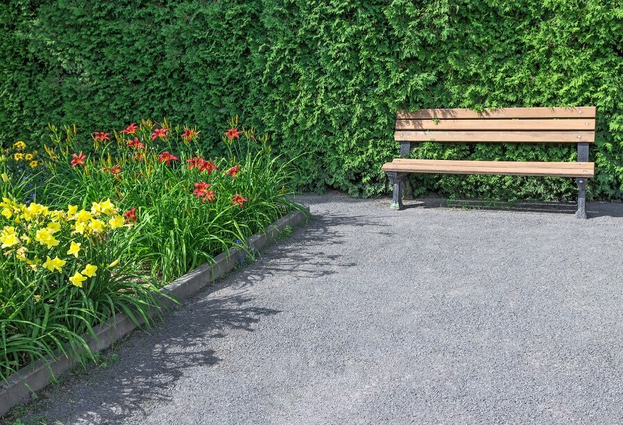 Un jardin en gravier avec un banc et des jolies plantes