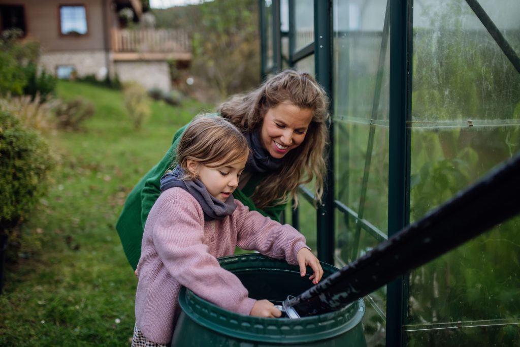 maman et sa fille qui récupère l'eau du réservoir de pluie