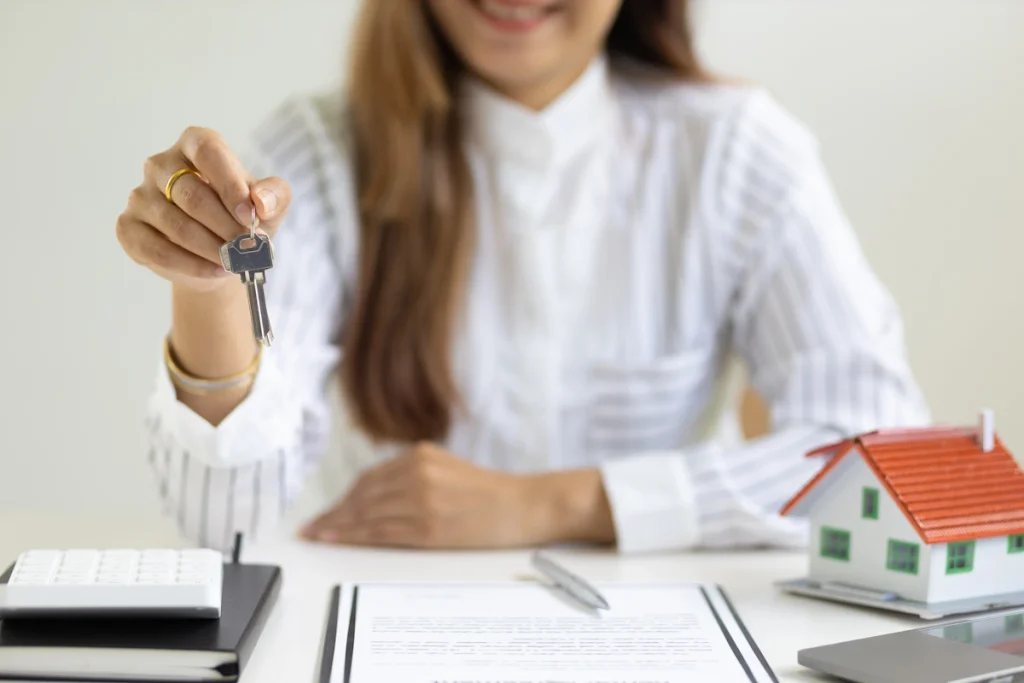 Une femme assise à son bureau qui tend des clefs