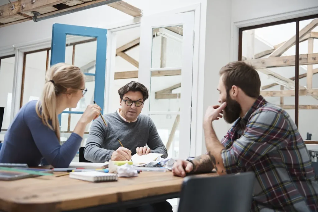 deux hommes et une femme en pleine discussion autour d'une table