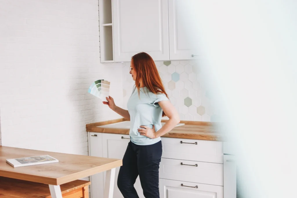 Une femme avec un nuancier qui regarde les couleurs à mettre sur le mur de sa cuisine