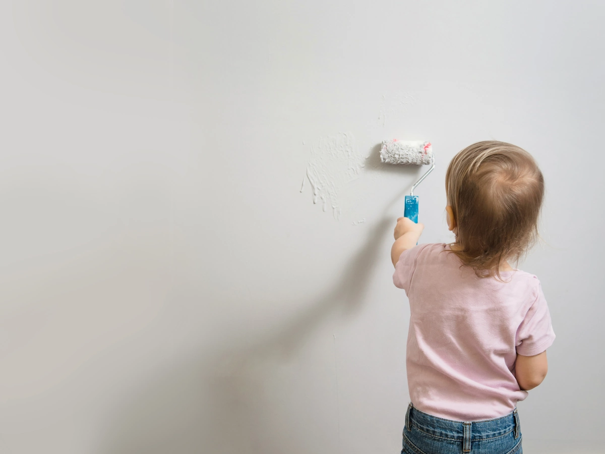 Un enfant qui applique une couche de sous-couche sur un mur avec un petit rouleau