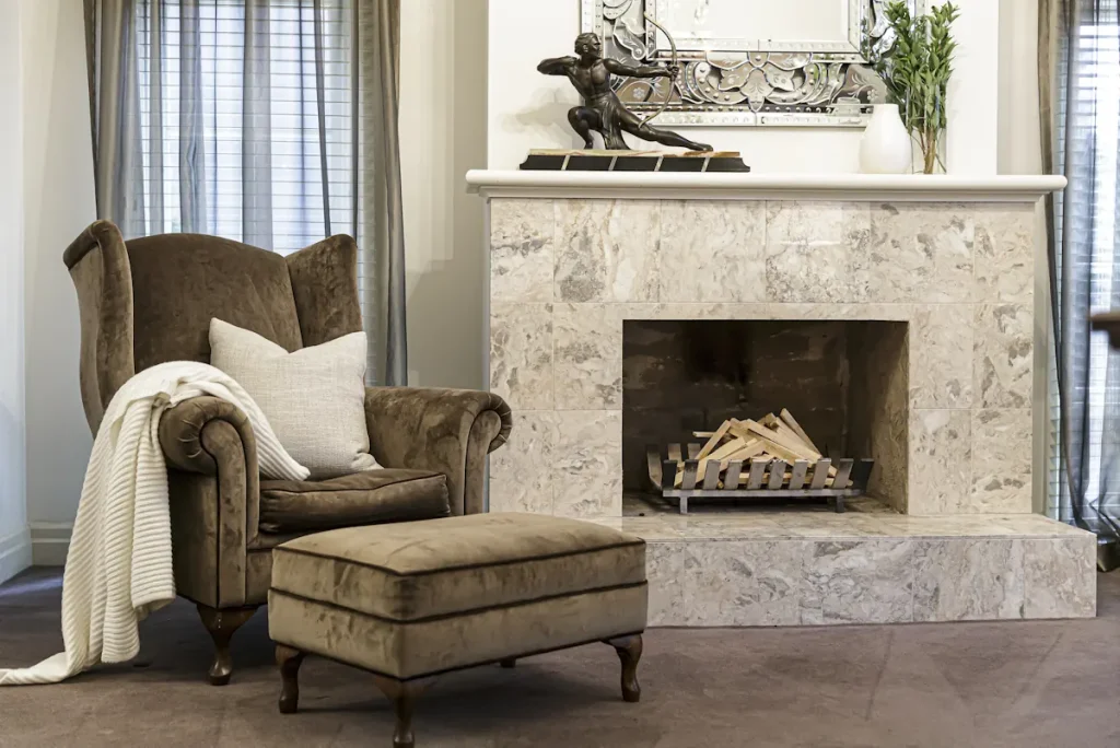 Une cheminée à côté d'une chaise en velours