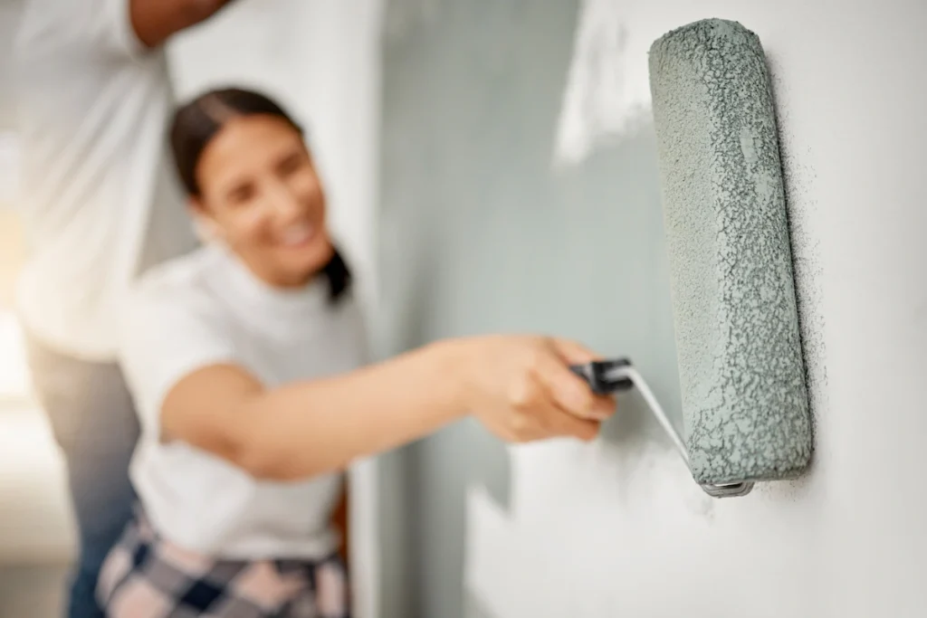 Une femme qui applique un enduit gris sur un mur