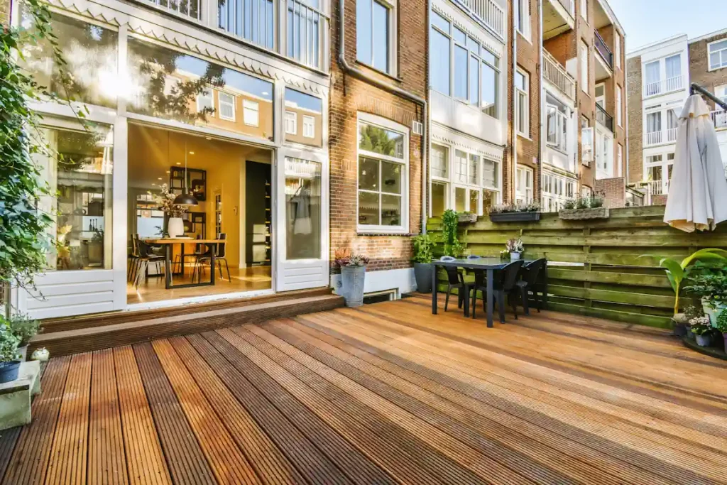 Une terrasse en bois rattachée à une façade de maison blanche