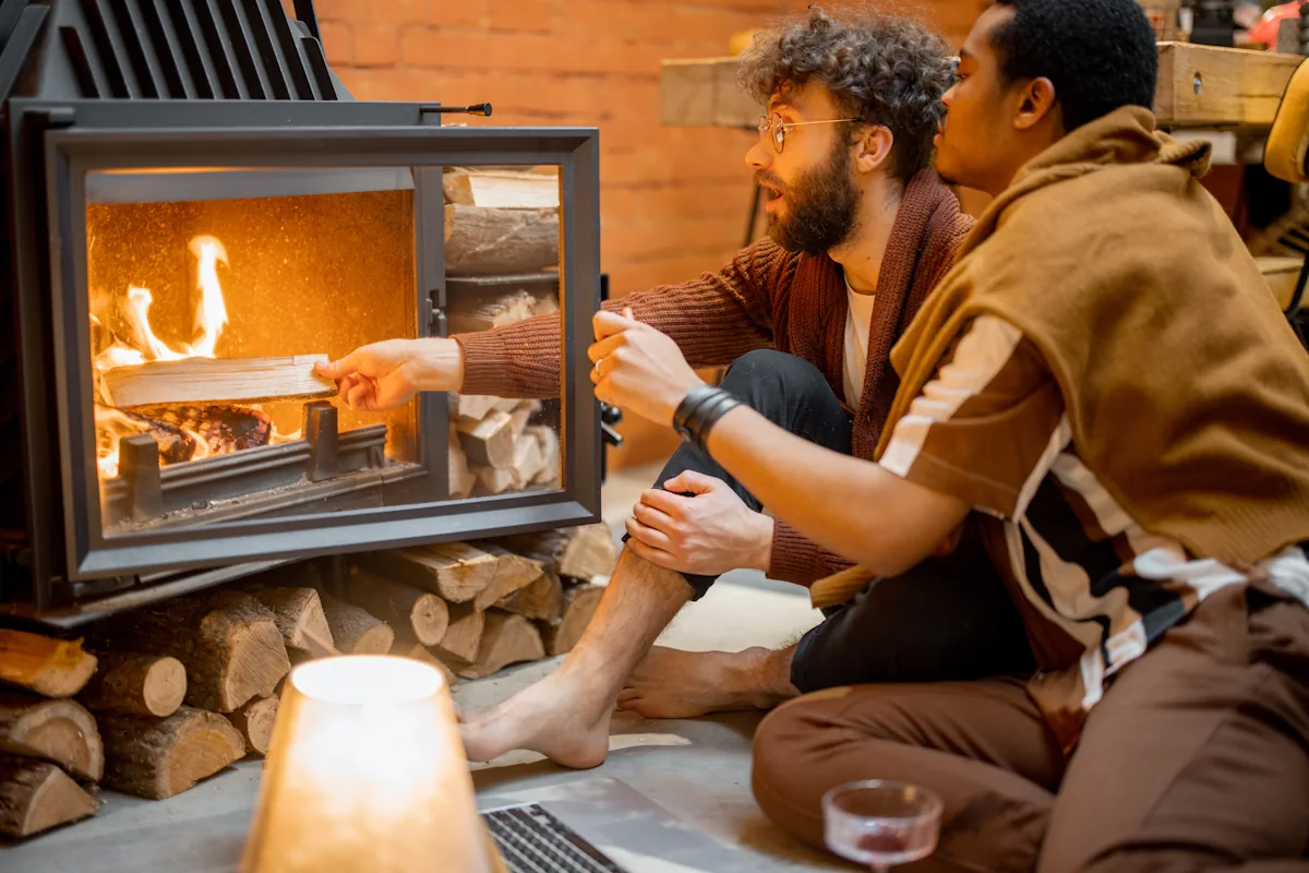 Une femme et un homme qui ajoute du bois dans leur poêle