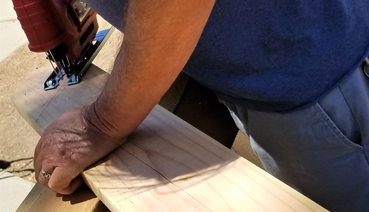 Un homme qui coupe du bois avec un scie à main