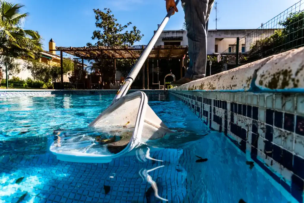 Un homme qui nettoie une piscine avec une épuiisette