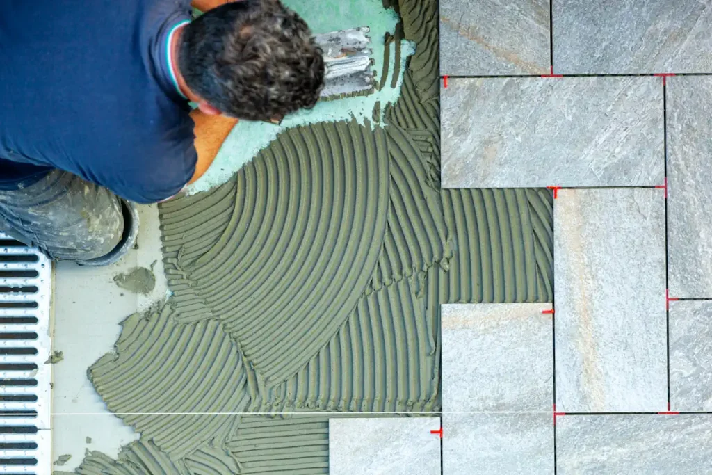 Un homme qui pose des carreaux sur le sol