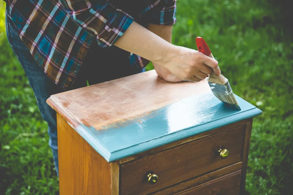 Un homme qui peint un meuble en bois