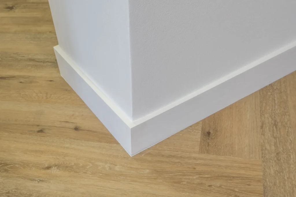 Un mur de maison blanc avec une plinthe blanche