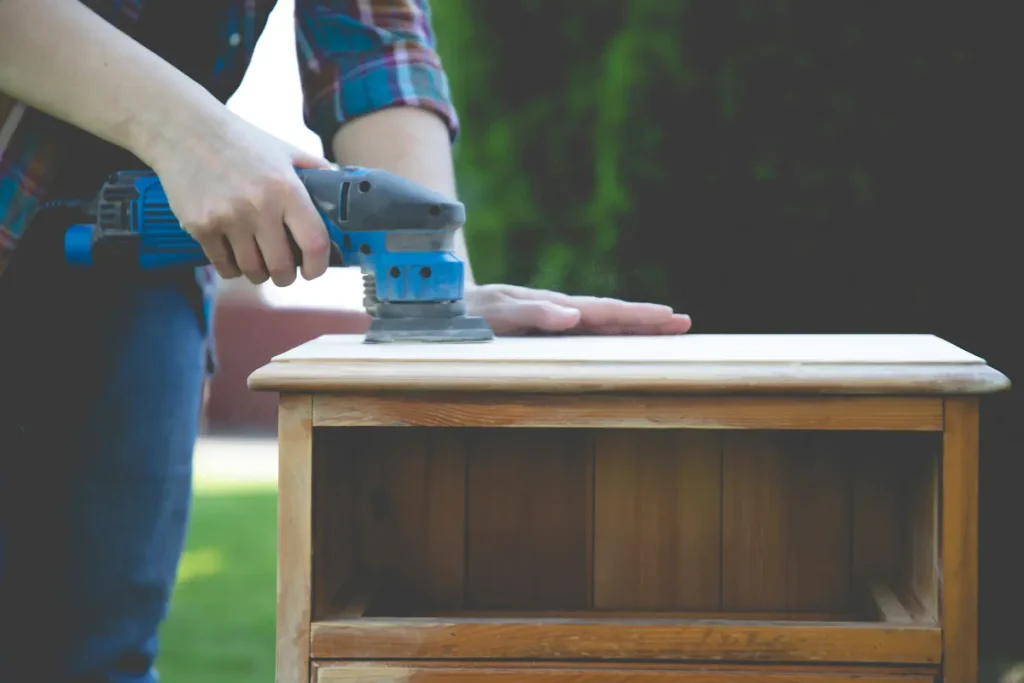 Un homme qui ponce un meuble en bois