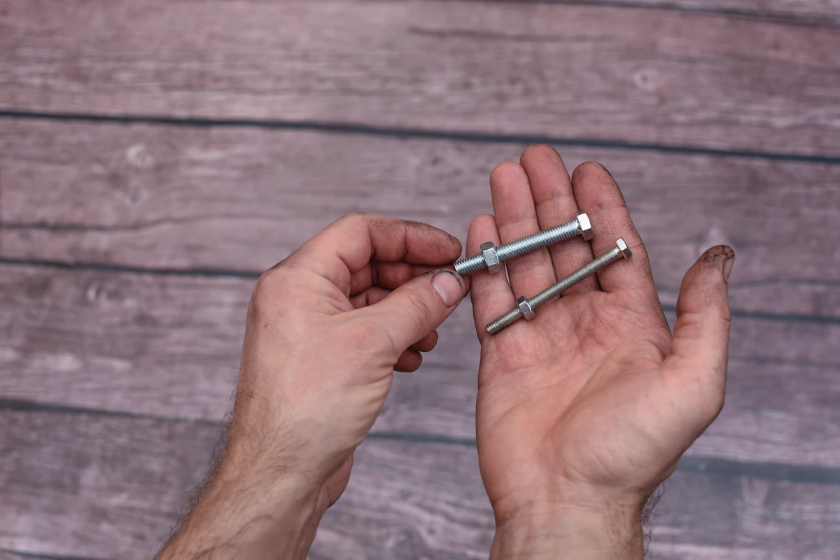 Une personne qui tient deux types de vis dans sa main