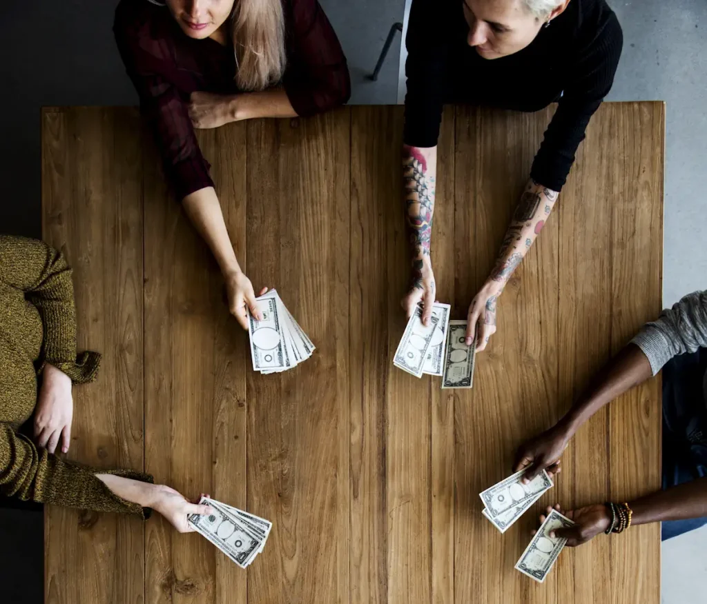 Un groupe de personne assis autour de la table qui tient des billets d'argent
