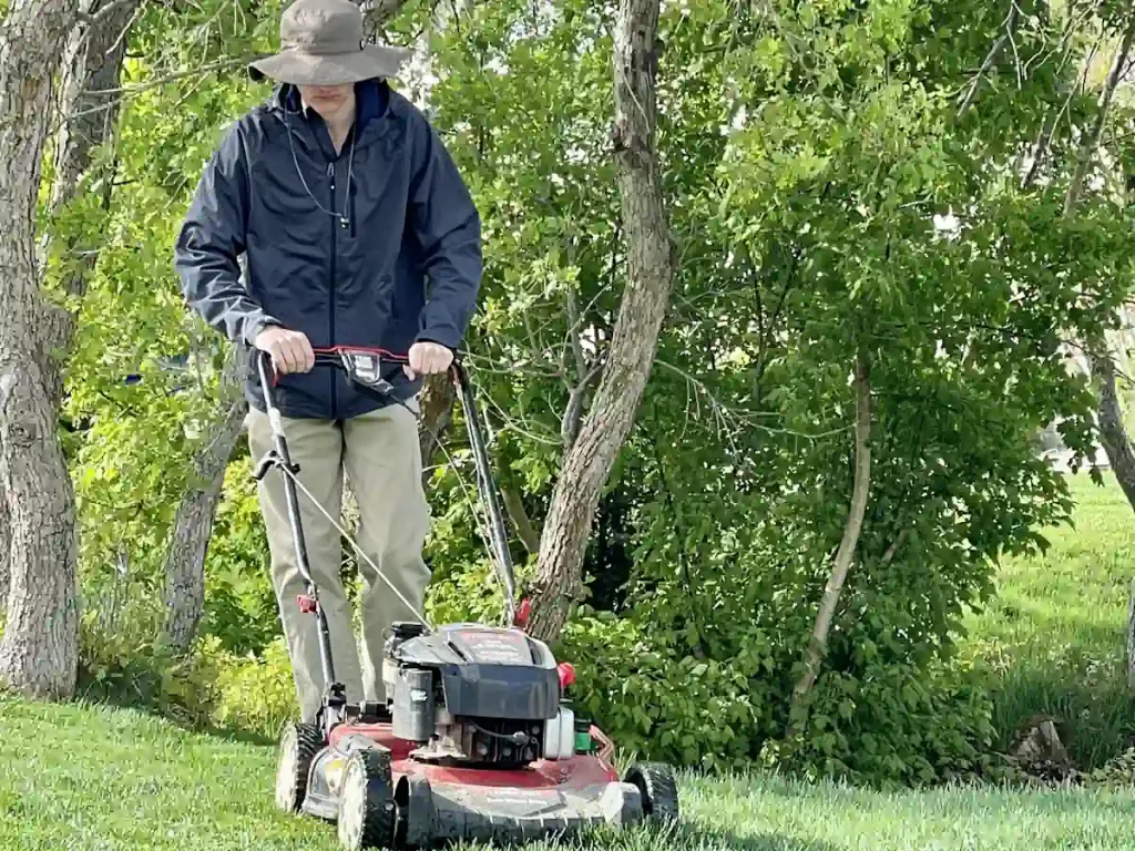 un homme avec une tondeuse qui passe dans un jardin
