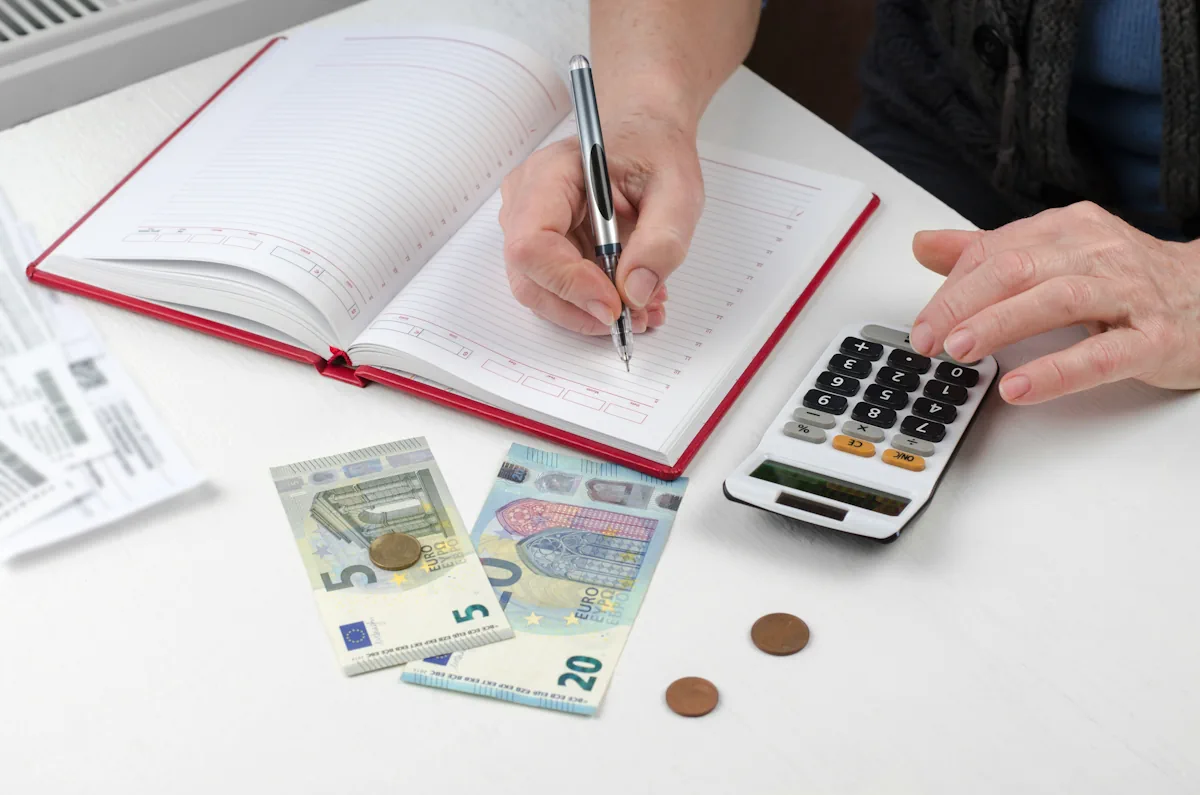 Une personne qui fait des calculs sur un carnet et avec une calculatrice