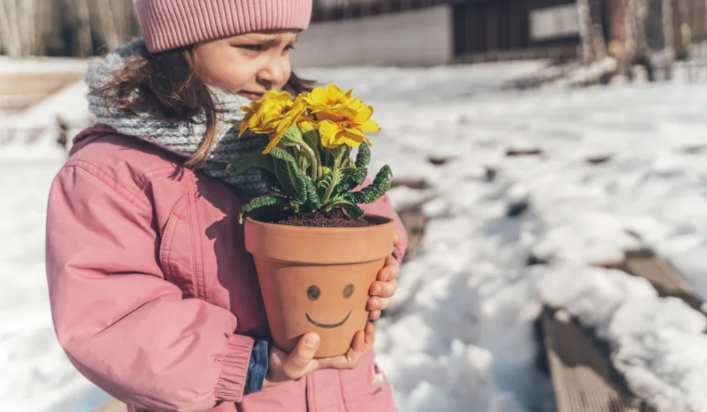 Une petite fille qui porte une fleur dans un pot