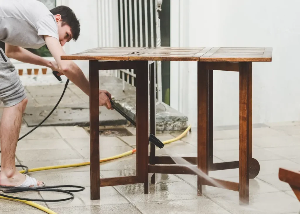 Un homme qui nettoie une table en bois avec un jet à haute pression