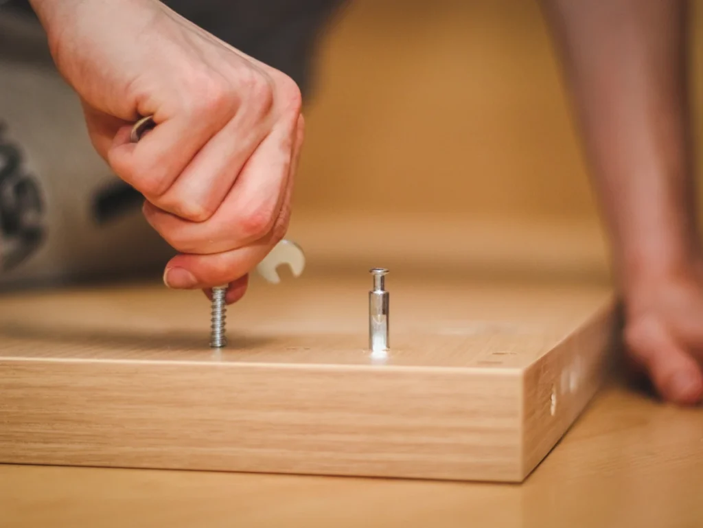Un homme qui tourne un vis sur un morceau de bois