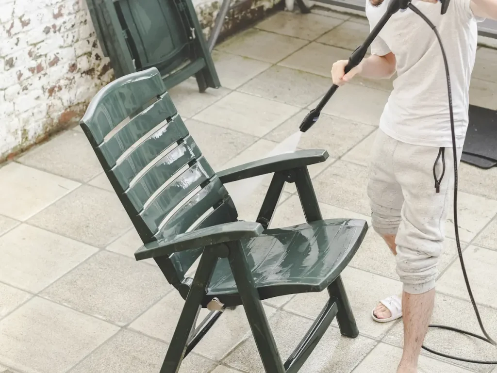 Un homme qui nettoie une chaise en plastique noir au jet