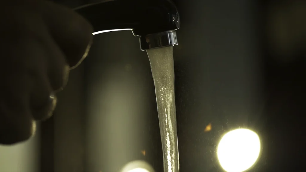 Une personne qui tient un robinet où coule de l'eau