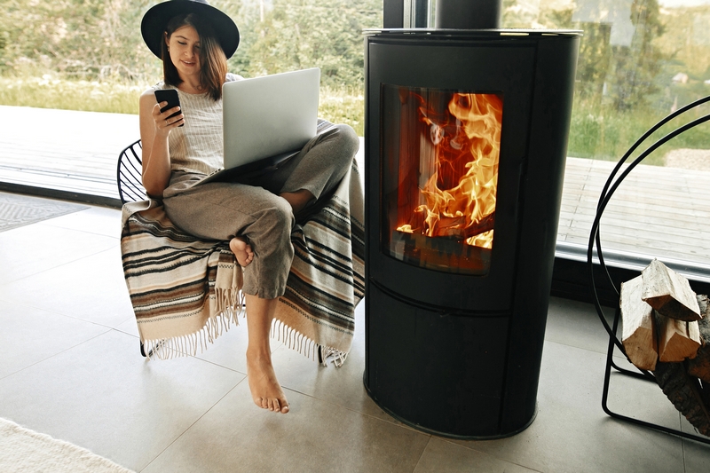 femme assise confortablement à côté de son poêle à bois