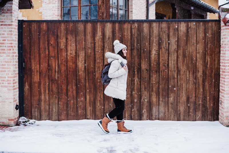 femme qui passe devant un portail en bois