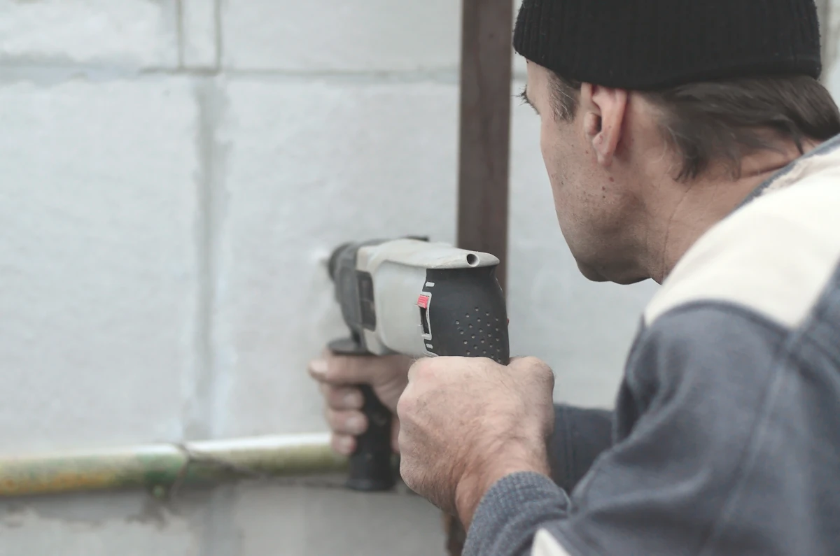 Un homme qui fixe une cheville sur un béton