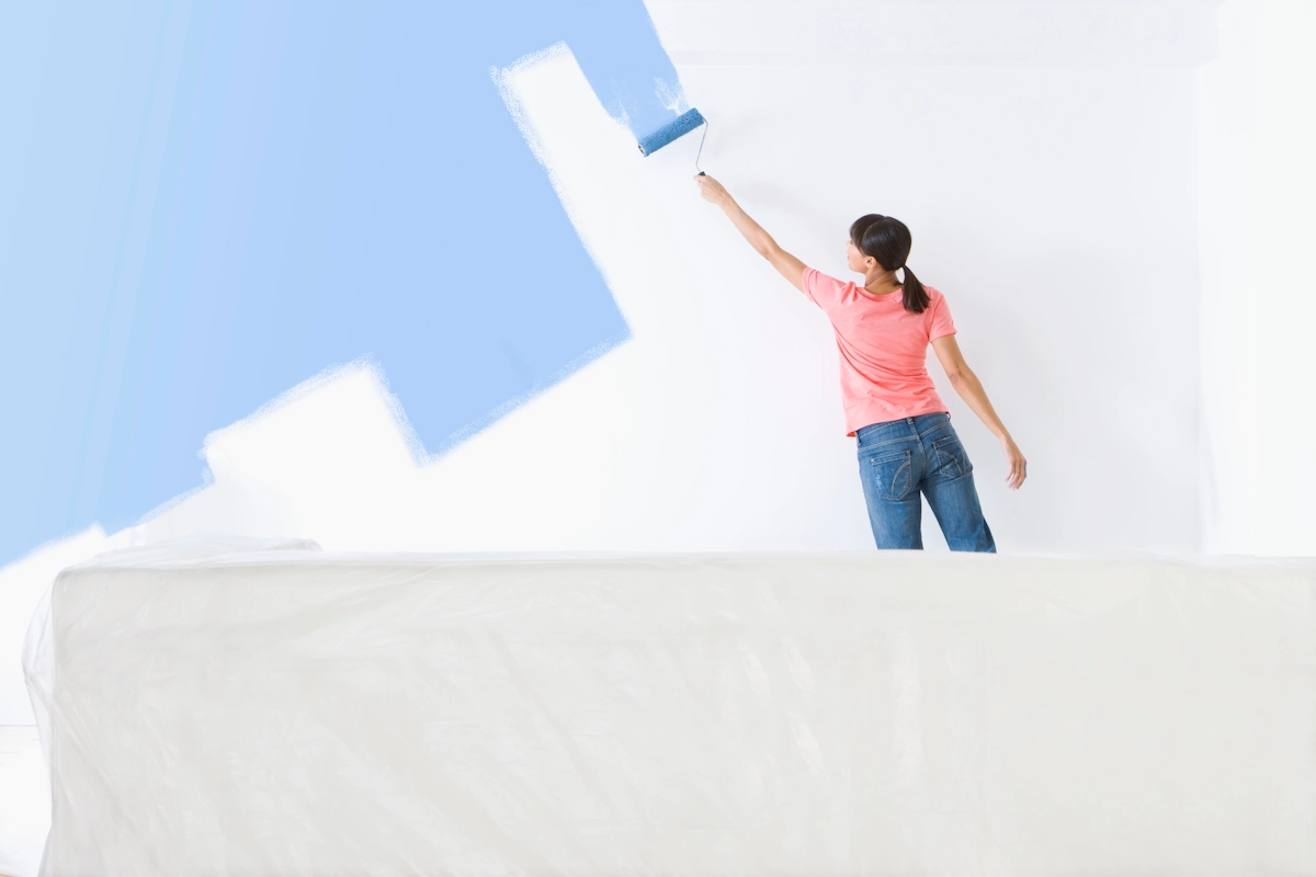Une femme qui peint un mur en placo en bleu