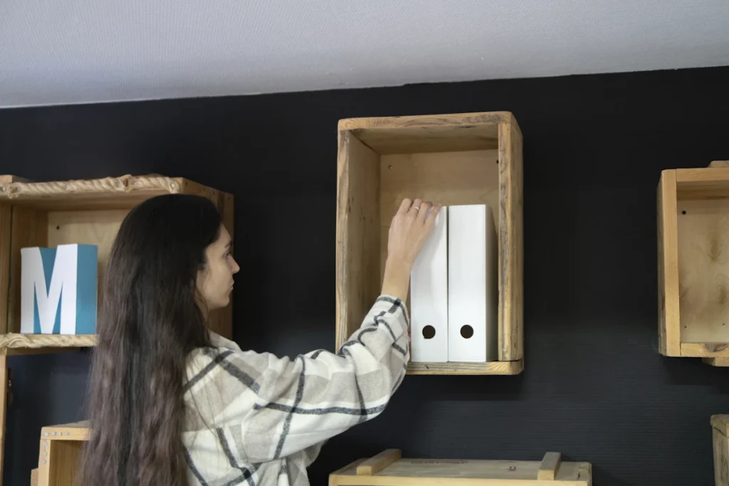 Une femme qui met des accessoires sur un étagère fixé sur un mur en placo