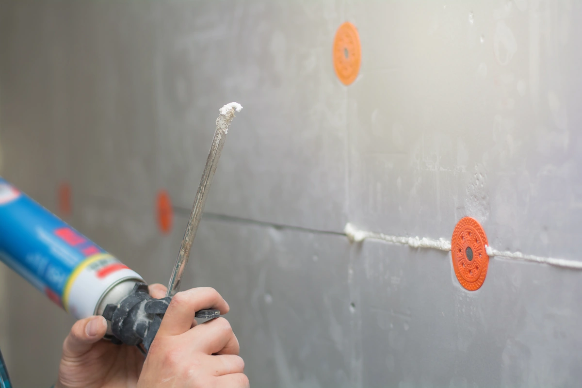 Une personne qui a mis des joints silicone maladroitement sur du carreau