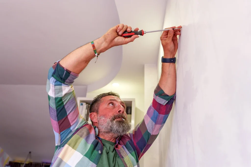 Une personne qui essaie de fixer une cheville dans un mur qui ne tient pas