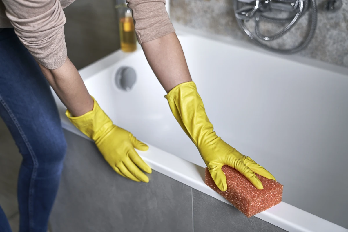 Une personne qui nettoie baignoire avant pose joint silicone avec alcool isopropylique