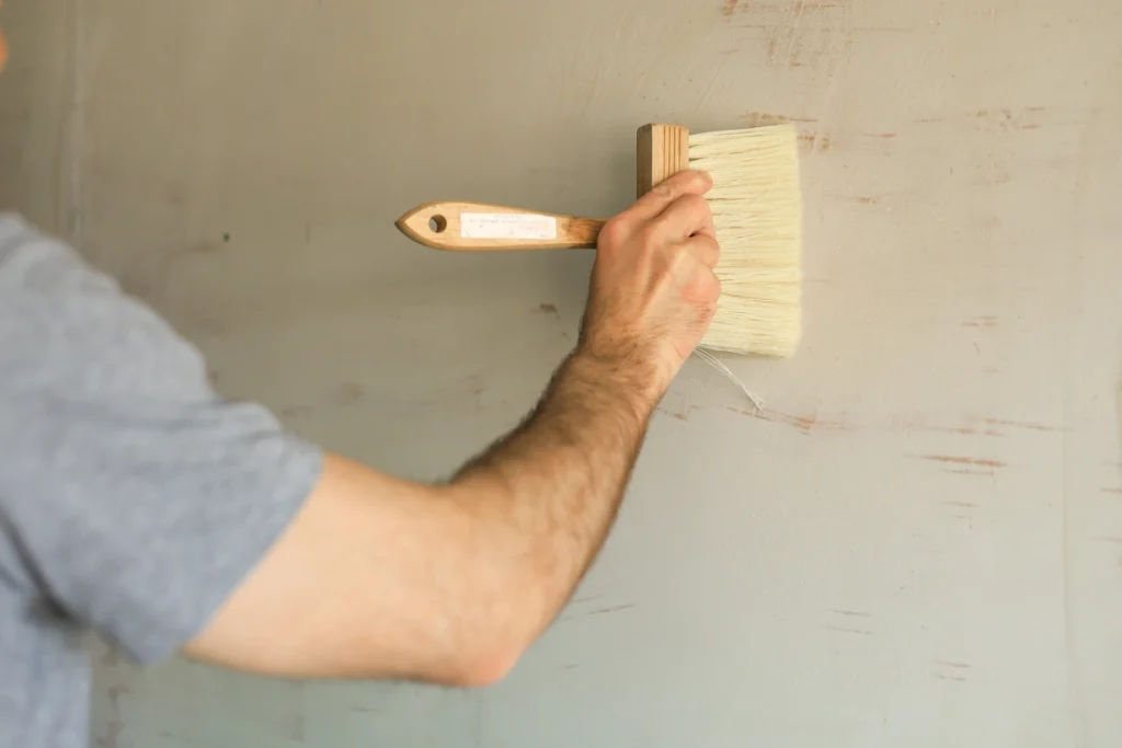 Une personne qui applique un primaire d'accrochage sur un mur