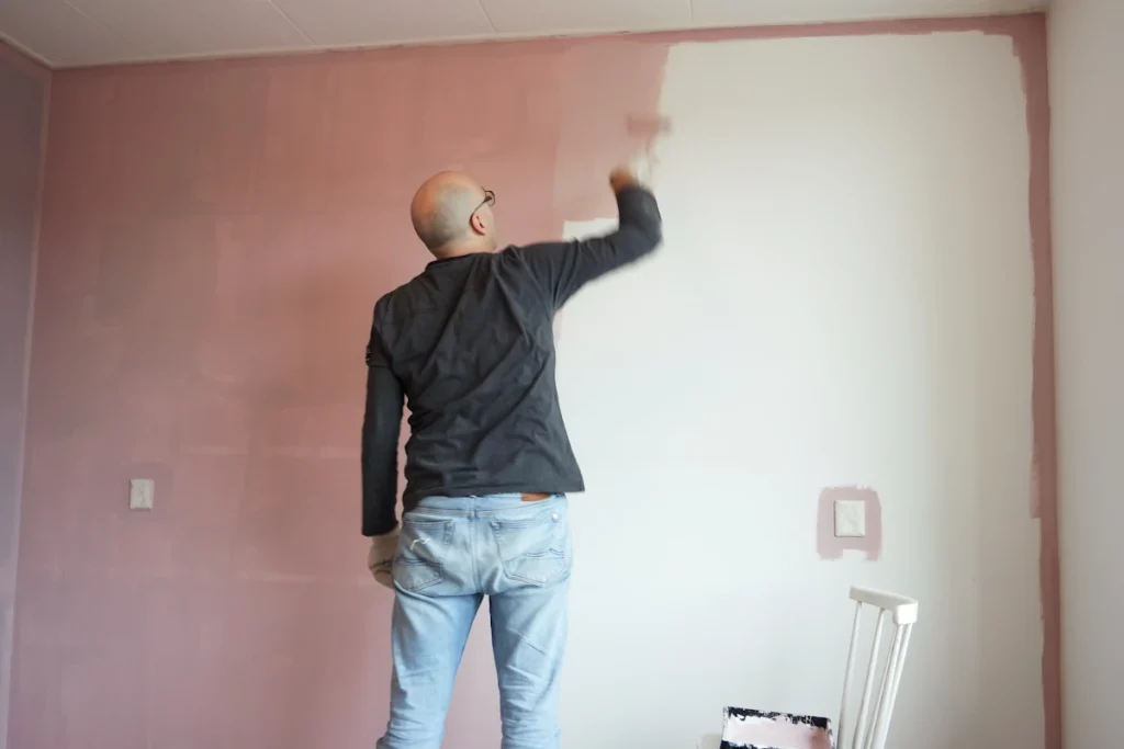 Un homme qui applique une sous-couche obligatoire peinture mur neuf placo
